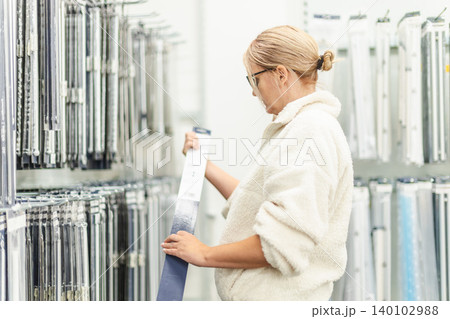 Woman selecting curtain rail in home improvement store department 140102988
