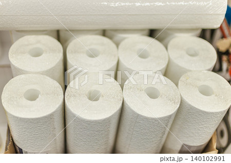 White textured wallpaper rolls stacked in home improvement store for renovation projects 140102991