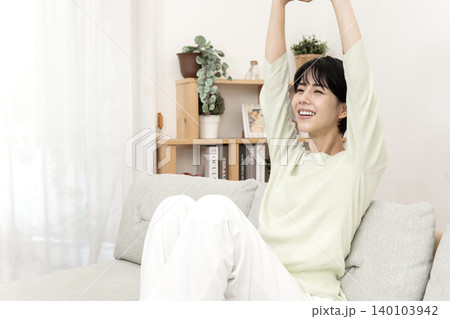 ソファーでストレッチをしてリフレッシュする女性 ソファーでストレッチをしてリフレッシュする女性 140103942
