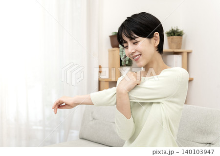 ソファーでストレッチをしてリフレッシュする女性 ソファーでストレッチをしてリフレッシュする女性 140103947