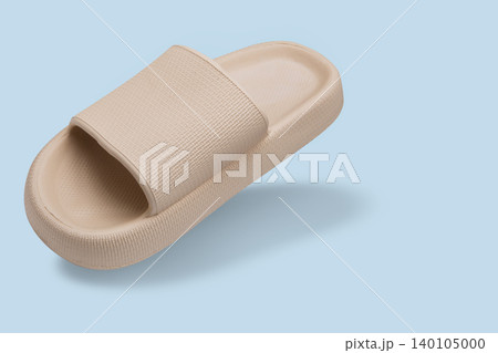 Levitating beige platform cloud slide on pastel blue background. Floating foam pillow slipper with copy space, creative product photography. Levitating beige platform cloud slide on pastel blue background. Floating foam pillow slipper with copy space, creative product photography. 140105000
