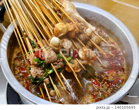 Spicy Sichuan style hot pot skewers simmering in a flavorful chili broth Spicy Sichuan style hot pot skewers simmering in a flavorful chili broth 140105695