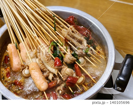 Spicy Sichuan style hot pot skewers simmering in a flavorful chili broth Spicy Sichuan style hot pot skewers simmering in a flavorful chili broth 140105696
