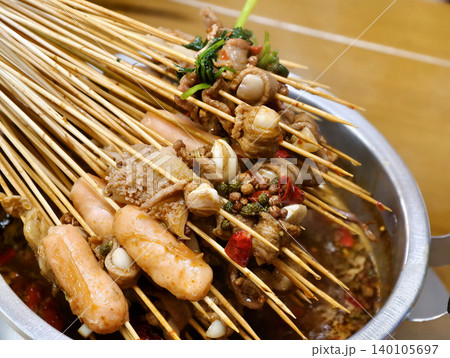 Spicy Sichuan style hot pot skewers simmering in a flavorful chili broth Spicy Sichuan style hot pot skewers simmering in a flavorful chili broth 140105697