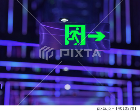 Glowing green emergency exit sign in a futuristic neon-lit interior with vibrant purple and blue lights. Glowing green emergency exit sign in a futuristic neon-lit interior with vibrant purple and blue lights. 140105701