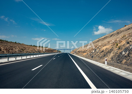 Empty asphalt road with white lines and guardrails Empty asphalt road with white lines and guardrails 140105750