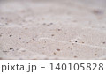 Sand patterns on beach with small stones and shells at low tide during daylight near ocean waves 140105828