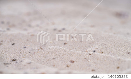 Sand patterns on beach with small stones and shells at low tide during daylight near ocean waves 140105828