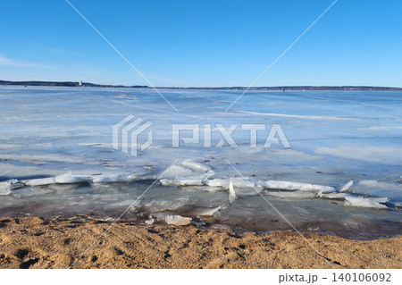 Frozen lake surface with ice shards on sandy beach Frozen lake surface with ice shards on sandy beach 140106092