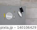 Sewing supplies are arranged on a table with thread, needles, and a button for a crafting project 140106429