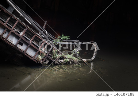A skeletal, heavily rusted escalator descends directly into a dark, flooded abyss. Submerged in murky, stagnant water, the metallic base casts a distorted, glass-like reflection of decay. Vivid green A skeletal, heavily rusted escalator descends directly into a dark, flooded abyss. Submerged in murky, stagnant water, the metallic base casts a distorted, glass-like reflection of decay. Vivid green 140107199