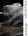 a ghostly haze drifts through a decaying, multi-tiered atrium, where the skeletal remains of rusted escalators slice across a dark void and reflect flawlessly in a pool of stagnant rainwater below. 140107303