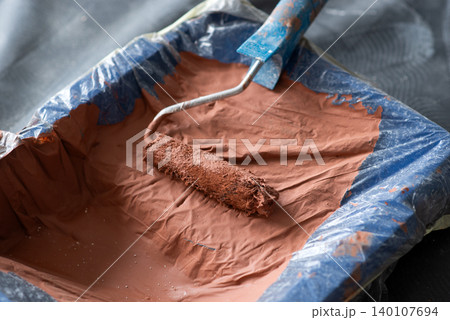 Paint roller in a plastic-lined tray filled with thick brown paint during home renovation Paint roller in a plastic-lined tray filled with thick brown paint during home renovation 140107694