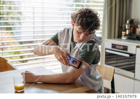 Teen girl with diabetes scanning glucose level using CGM sensor and smartphone. Teen girl with diabetes scanning glucose level using CGM sensor and smartphone. 140107979