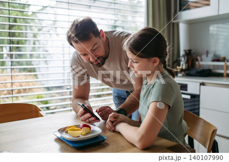 Father checking blood sugar level of diabetic teenage daughter using glucose meter. Father checking blood sugar level of diabetic teenage daughter using glucose meter. 140107990