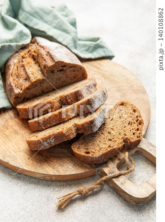 Slicing fresh whole grain rye bread on wooden board 140108862