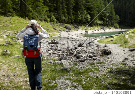 Woman hiker with backpack walking on a mountain path in the Austrian Alps, highlighting exploring remote mountain landscapes Woman hiker with backpack walking on a mountain path in the Austrian Alps, highlighting exploring remote mountain landscapes 140108891
