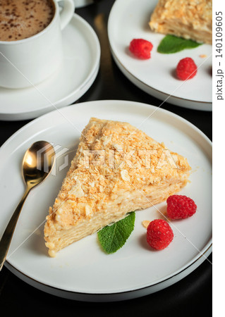 Sliced Napoleon cake on a white wooden table. Classic dessert Sliced Napoleon cake on a white wooden table. Classic dessert 140109605