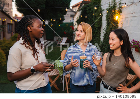 Diverse women friends enjoying backyard summer party talking and smiling 140109699