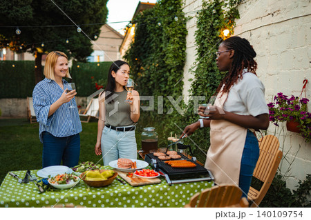 Diverse women friends enjoying backyard barbecue party together Diverse women friends enjoying backyard barbecue party together 140109754