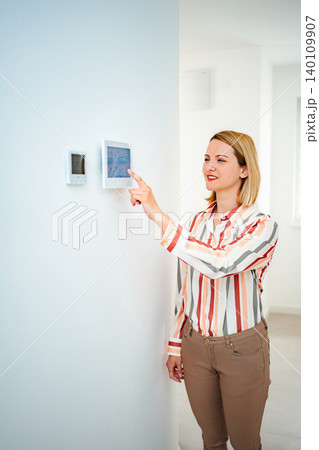 Woman controlling smart home automation system on wall display Woman controlling smart home automation system on wall display 140109907