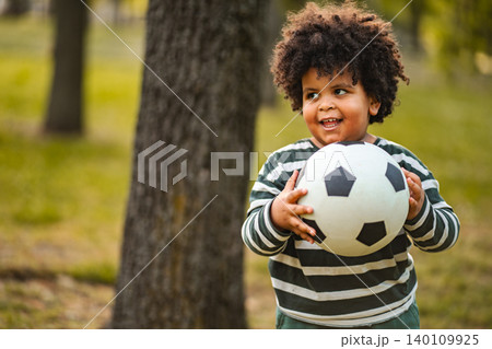 Happy little boy holding soccer ball in park Happy little boy holding soccer ball in park 140109925