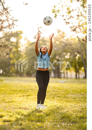 Young girl playing with soccer ball in park Young girl playing with soccer ball in park 140109928