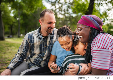 Multiracial family laughing together experiencing happiness in park 140109941