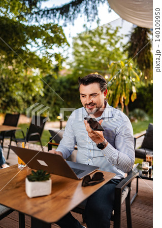 Man working remotely using laptop and voice message Man working remotely using laptop and voice message 140109950
