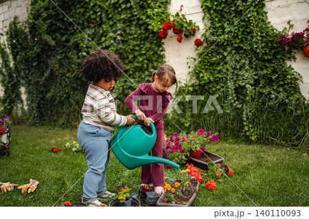 Children watering flowers in the garden together Children watering flowers in the garden together 140110093