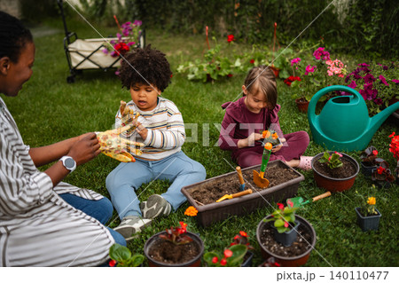 Mother and children planting flowers in backyard garden Mother and children planting flowers in backyard garden 140110477