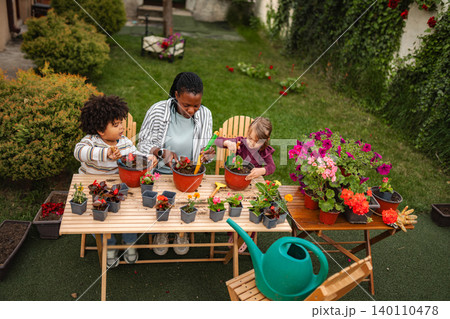 Mother and children planting flowers in backyard garden Mother and children planting flowers in backyard garden 140110478