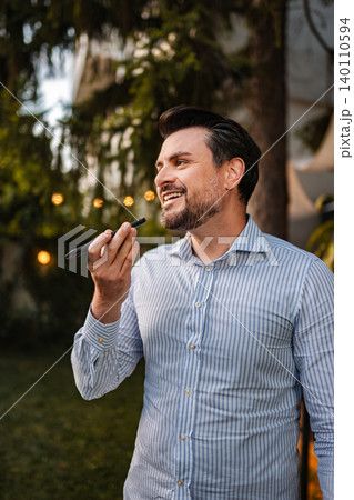 Man recording voice message using smartphone outdoors Man recording voice message using smartphone outdoors 140110594