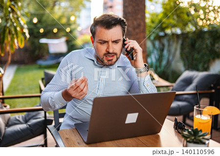 Stressed businessman having difficult phone call working outdoors 140110596