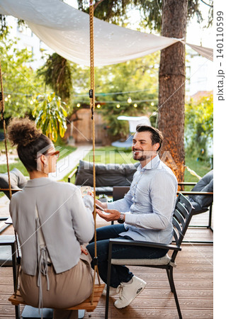 Couple sitting outdoors talking and smiling in garden Couple sitting outdoors talking and smiling in garden 140110599