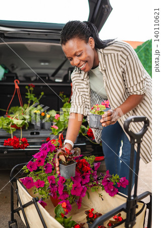 African American woman loading garden plants into cart 140110621