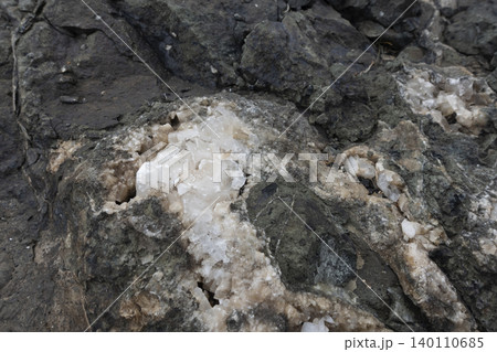Close-up of a raw calcite mineral formation embedded within a dark rock matrix Close-up of a raw calcite mineral formation embedded within a dark rock matrix 140110685
