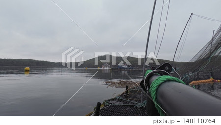 Large fish farm in the water with nets under cloudy sky as background 140110764