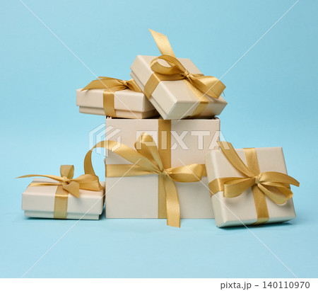 Stack of gift boxes with golden silk bows on blue background 140110970