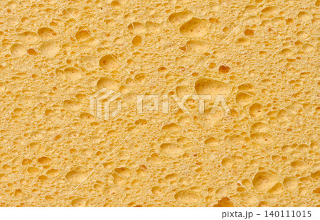 A full-frame macro shot of the porous texture of a yellow cellulose sponge for washing dishes and cleaning A full-frame macro shot of the porous texture of a yellow cellulose sponge for washing dishes and cleaning 140111015