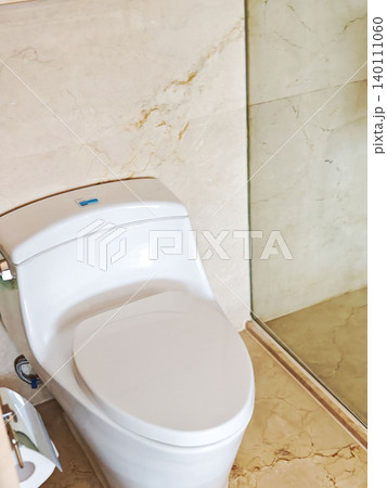Modern white toilet in a stylish bathroom with marble walls and glass shower enclosure, showcasing contemporary design and clean lines Modern white toilet in a stylish bathroom with marble walls and glass shower enclosure, showcasing contemporary design and clean lines 140111060