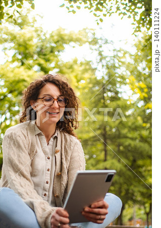 Young woman enjoying tablet outdoors relaxing in nature 140111224