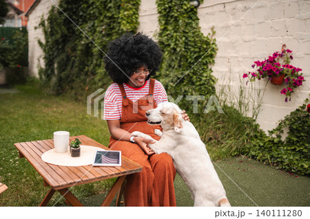 Young woman sitting in yard, petting happy dog 140111280