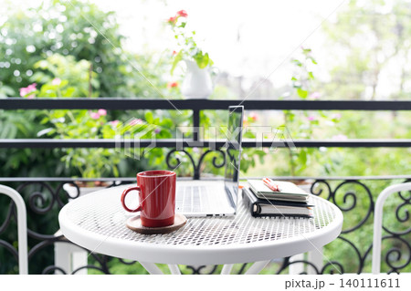 Red coffee cup and notebook on white metal table 140111611
