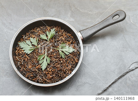 Edible mealworms , lat. Tenebrio molitor, in a frying pan on the stone table. 140111968