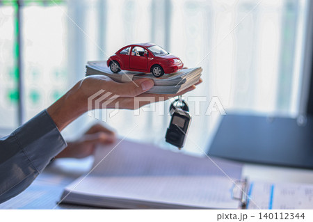 Singing a car contract. Hand carrying cash, car and car key. Concept for car loan, lease, insurance, buying or selling. Singing a car contract. Hand carrying cash, car and car key. Concept for car loan, lease, insurance, buying or selling. 140112344