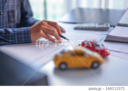 A man signing a contract for a car loan, lease, vehicle registration or insurance policy. Concept for Sales Contract, Financing Agreement, Insurance Policy, Vehicle Registration. 140112371