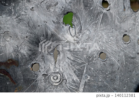 Bullet holes of different calibers on piece of sheet steel 140112381