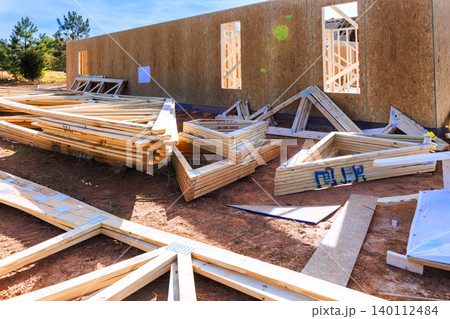 Wooden beams panels are arranged on ground near walls of building under construction Wooden beams panels are arranged on ground near walls of building under construction 140112484