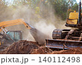 Heavy machinery removes soil debris at construction site preparing area for upcoming work 140112498